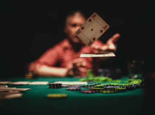 One mature man playing poker late by night, throwing playing cards on table.