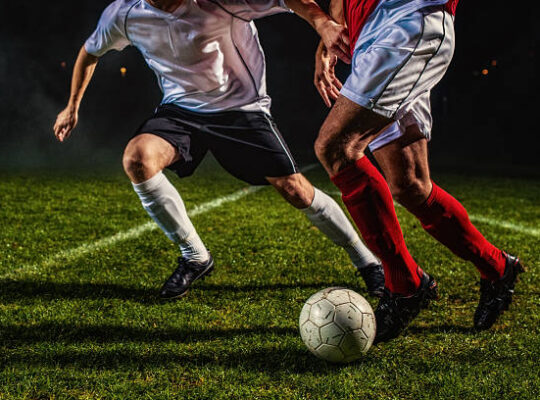 Two soccer players challenging for the ball, low angle view.